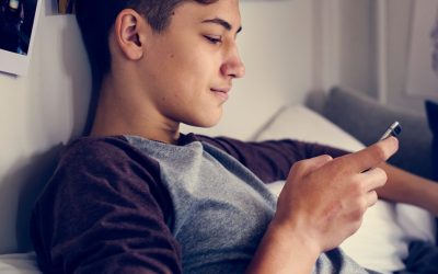 Teenage boy using smartphone in a bedroom social media concept