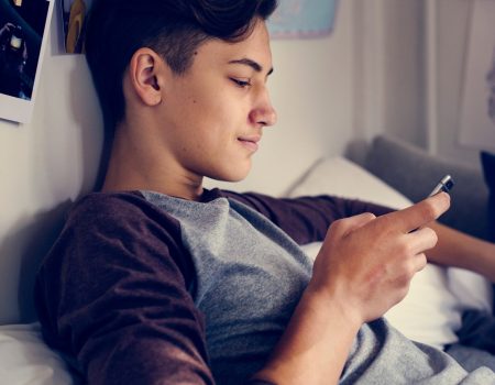 Teenage boy using smartphone in a bedroom social media concept